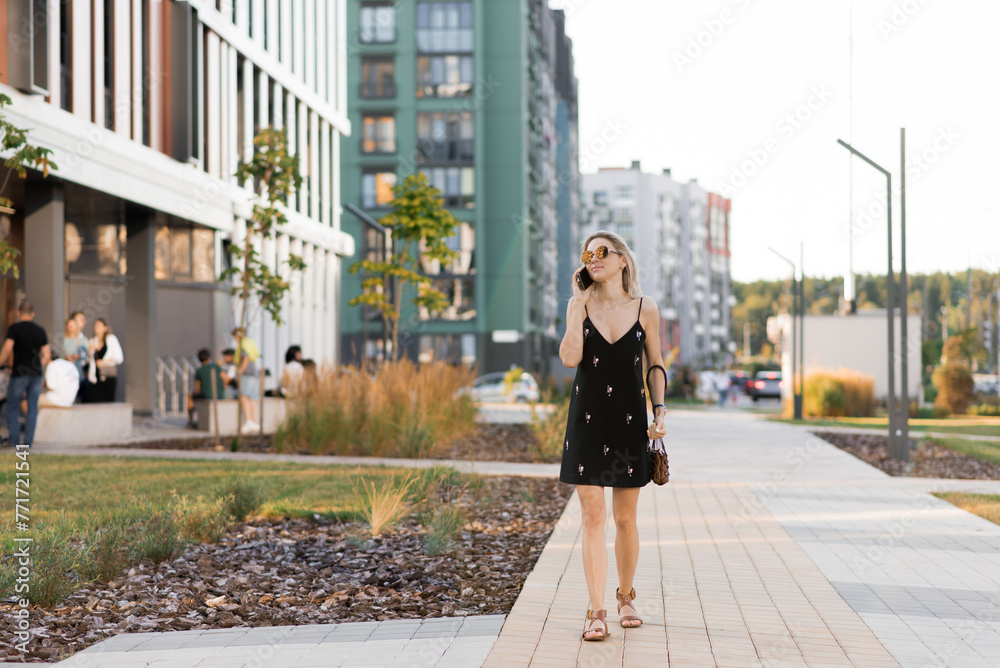 Young woman walking on city streets with while talking on her phone