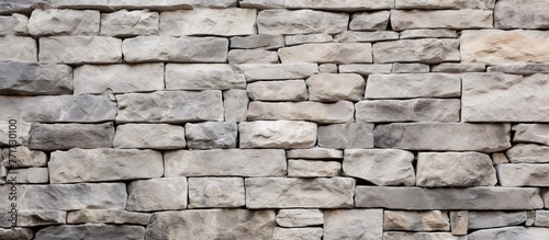 A detailed close up of a stone wall with a lot of rectangular bricks in a beige color. The intricate pattern of the brickwork highlights the composite material of this sturdy building material