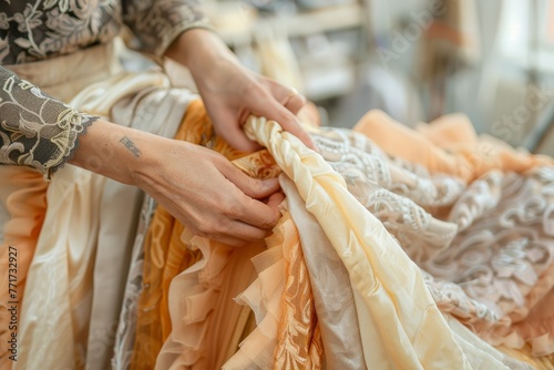 Fashion designer meticulously working on the ornate details of a ruffled dress in a bright studio, focus on hands and fabric, soft background, peach fuzz colors