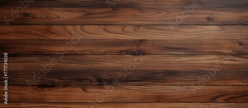 A closeup shot of a brown hardwood plank flooring with a blurred background, showcasing the natural wood grain pattern and beige tones