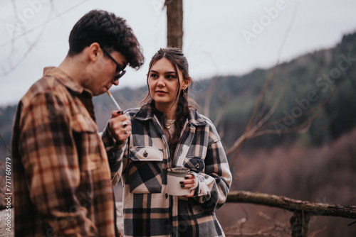 A loving couple stands close in a serene outdoor setting, sharing quality time and a warm drink, conveying a sense of companionship and connection.