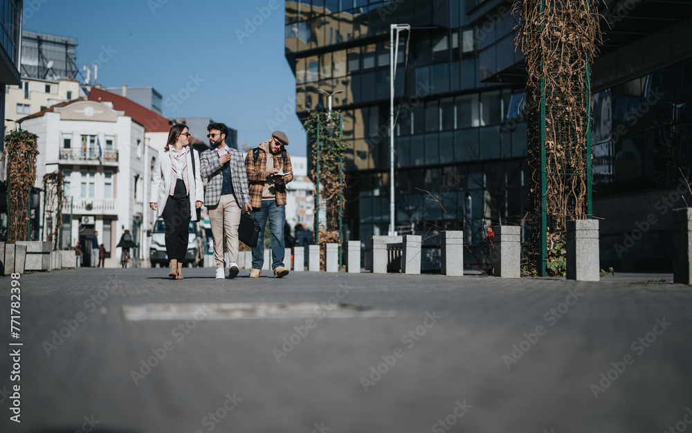 A group of young professionals having an informal business discussion while walking outdoors in an urban setting, analyzing market trends.