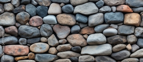 A stone wall made of rocks of various sizes and colors creates a stunning pattern, showcasing the beauty of natural materials as a building material in flooring and bedrock art