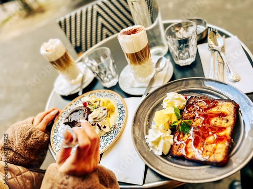 Hands of a woman holding a cup of cappuccino with chocolate cake and ice cream in Paris cafe, France