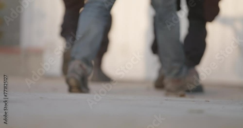 Swat, military, or black military boots moving in coordination. Preparing for raid. Walking on concrete, Low angle of feet. High intensity movement. concrete, Low angle of feet. Daytime photo