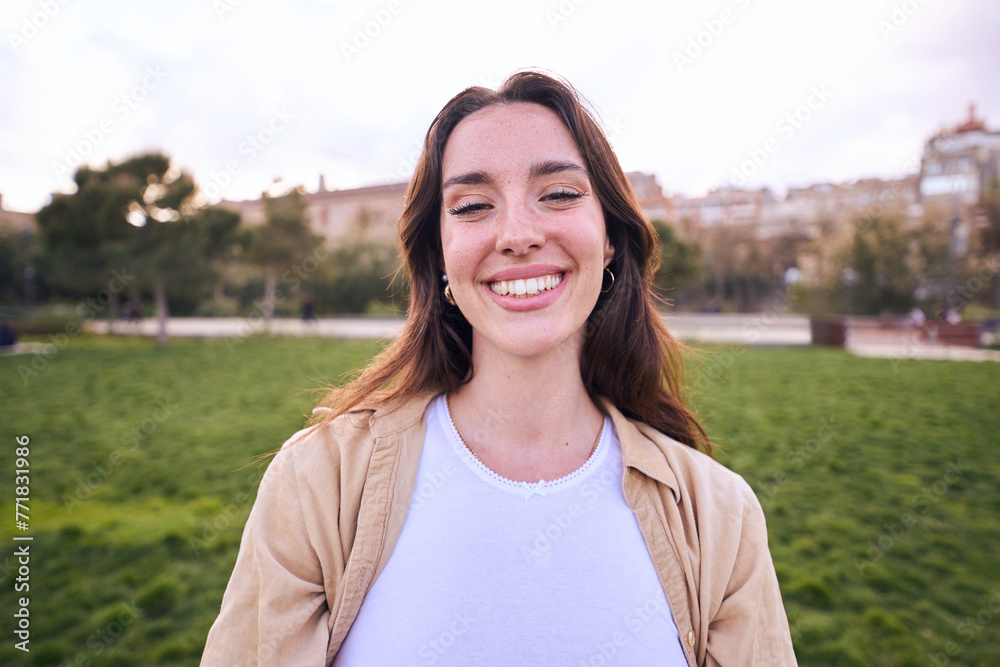Portrait of a woman looking at camera and smiling. Beautiful girl is happy and cute and is posing with positive expression. Attractive and confident Caucasian female enjoying outdoors