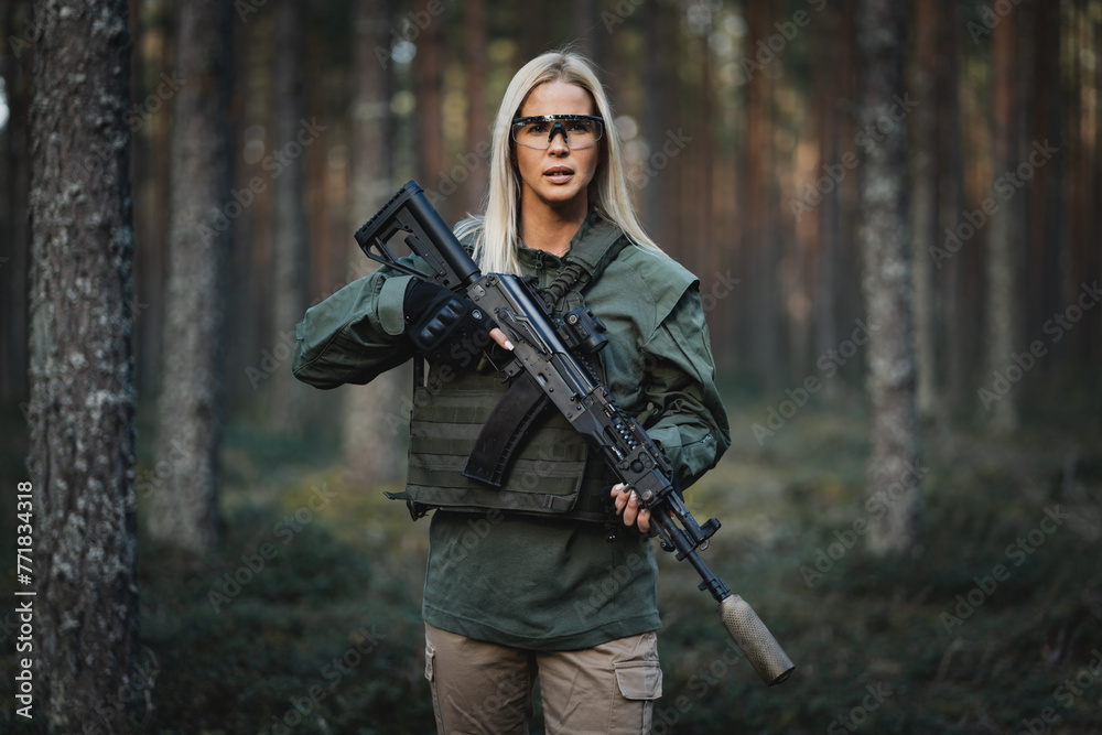 Beautiful military girl with a modern AK 12 rifle in the forest at war.