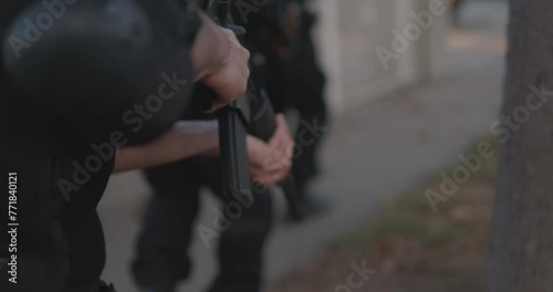 Police and Swat breaching fence a urban house. Following behind police officer close on assault rifle and hand. High intensity camera movement, Action photo
