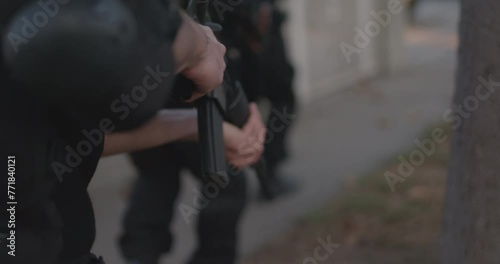 Police and Swat breaching fence a urban house. Following behind police officer close on assault rifle and hand. High intensity camera movement, Action
