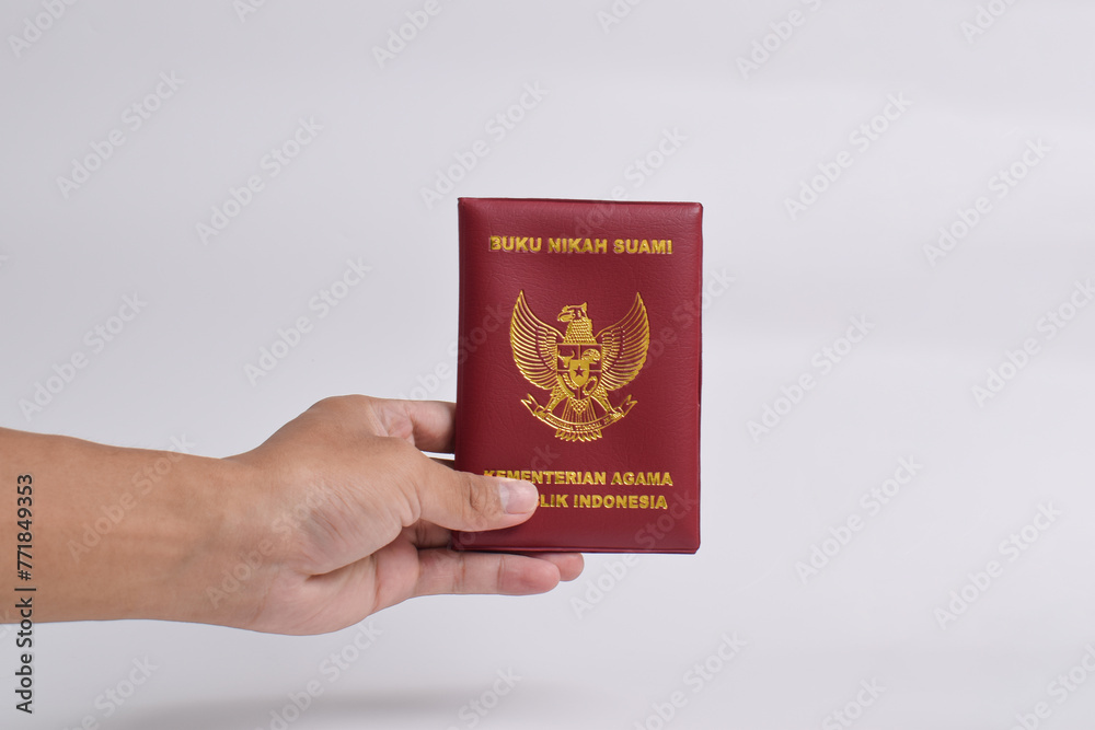 Hand holding husband's marriage book, Ministry of Religion of the Republic of Indonesia isolated on white background Hand holding husband's marriage book, Ministry of Religion of the Republic of Indonesia isolated on white background