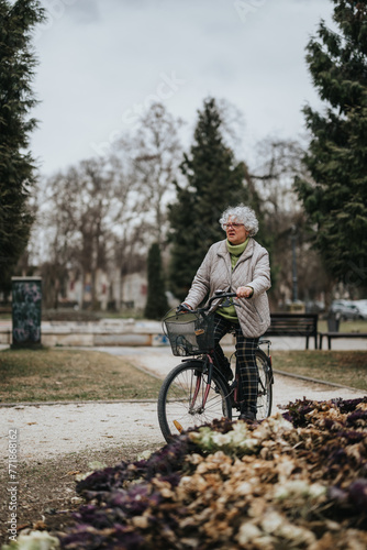 Fototapeta Naklejka Na Ścianę i Meble -  An independent mature woman leisurely cycling through a tranquil park setting, embracing an active lifestyle.