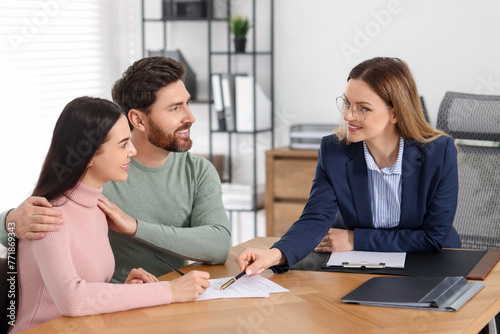 Happy couple signing document in lawyer's office