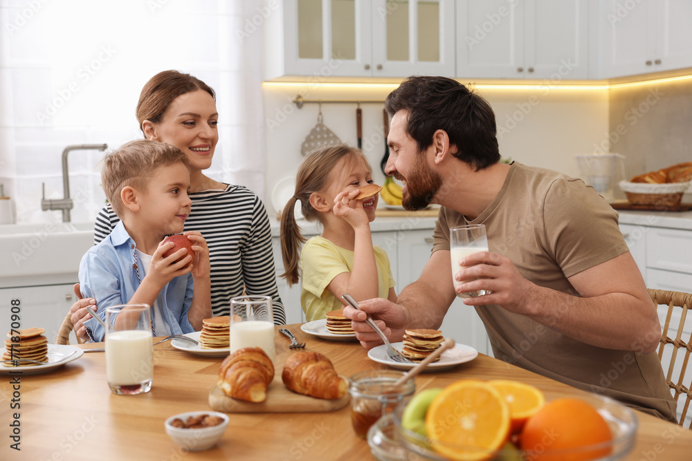 Happy family having fun during breakfast at table in kitchen Happy family having fun during breakfast at table in kitchen