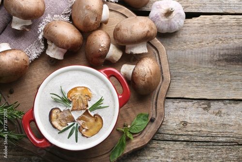 Delicious homemade mushroom soup in ceramic pot and fresh ingredients on wooden table, flat lay. Space for text