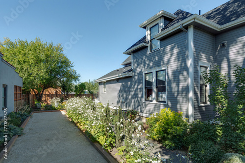 A quaint gray traditional cottage adorned with a vibrant flower garden, exuding charm and tranquility.