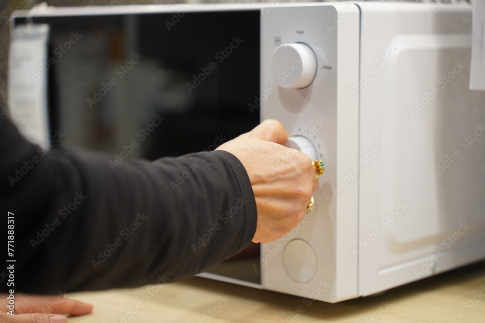 Naklejka premium woman using microwave oven in her kitchen