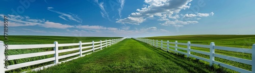 A pristine white picket fence borders a vibrant green field under a clear sky