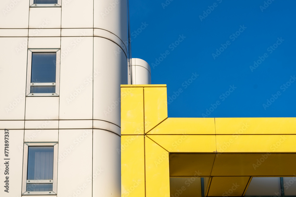 Obraz premium Modern, yellow, white building against clear blue sky.