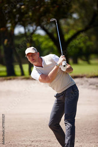 Man, golfer and hit with club on golf course in sand pit for stroke, point or strike by grass field in nature. Male person or sports player with swing on ball in dirt for par, game or outdoor match © peopleimages.com