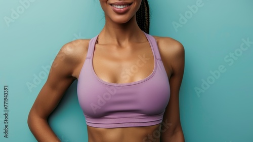 Cheerful woman in sports attire, close-up of smile and torso on teal background.