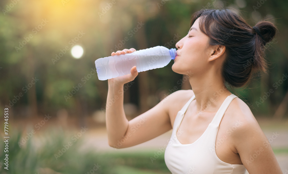 Female runner. Fit Asian young woman with white sportswear drinking water after running and enjoying a healthy outdoor. Fitness runner girl in public park. Wellness being concept Female runner. Fit Asian young woman with white sportswear drinking water after running and enjoying a healthy outdoor. Fitness runner girl in public park. Wellness being concept