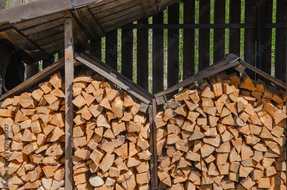 Firewood is prepared for the cold and stacked under a canopy Firewood is prepared for the cold and stacked under a canopy