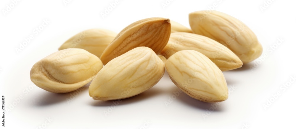 almonds scattered over white background. Some of the almonds were intact with the brown surface visible, while others were split almonds scattered over white background. Some of the almonds were intact with the brown surface visible, while others were split