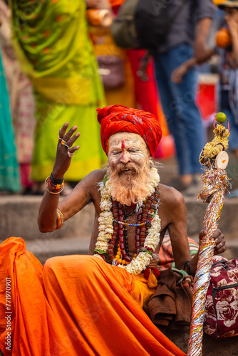 Portrait of an old sadhu baba with ash on his face sitting on ghats and blessings devotees.	 photo