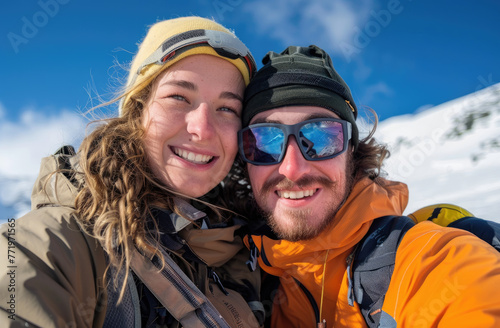 A young couple posing for the camera, holding their snowboards and goggles against an alpine backdrop, smiling at the viewer with big smiles on a sunny day.