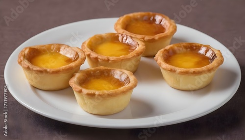 Homemade small egg tarts on a white plate, dessert Portuguese. on brown background.