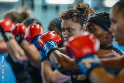 A dynamic shot showing a group of women energetically boxing while wearing red and blue gloves in a fitness class setting