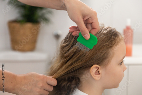 A woman helps to get rid of lice and parasites on the head of a little girl, combs her head with a special comb. Treatment of lice and nits