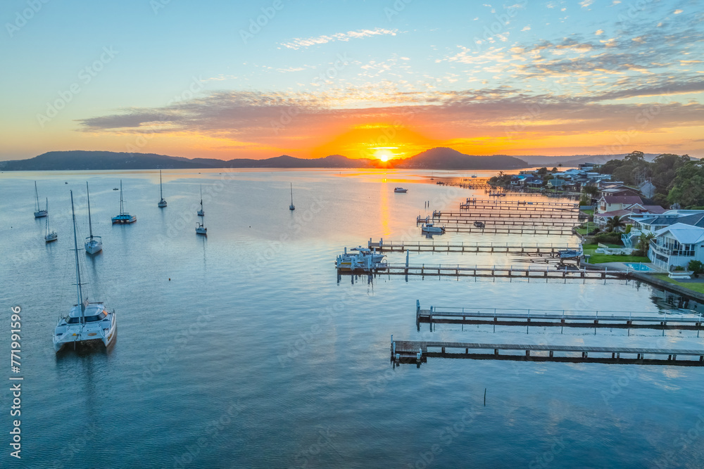 Fototapeta premium Sunrise over the water with boats and reflections