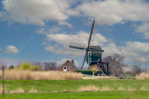Landscape with dike and historic Oukoopse molen with miller's cottage along the Enkele Wiericke in the Dutch province of Zuid Holland  photo