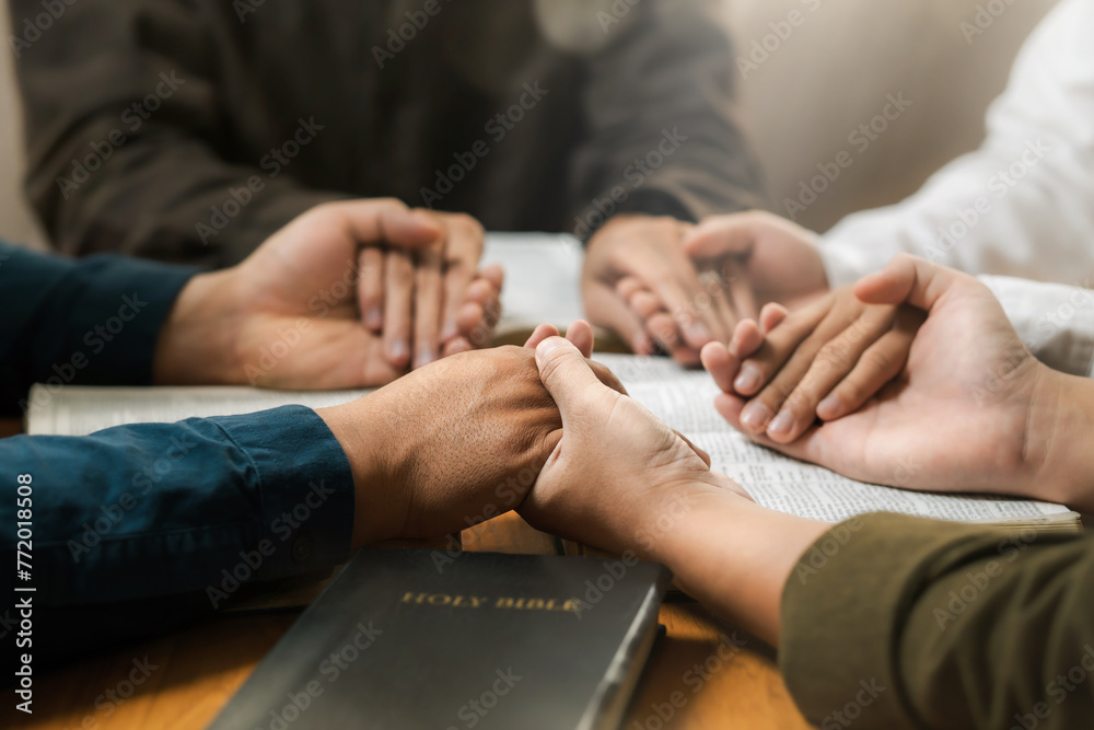 Group of young Christians praying, holding hands and praying together The concept of praying to God in the home as a team Pray to God with the Bible for forgiveness and faith.