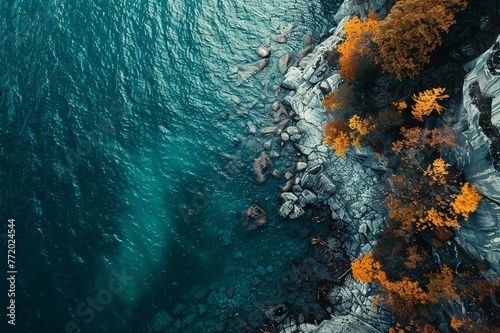 Aerial view of a rocky shore with autumn trees and turquoise water at lake biel in switzerland