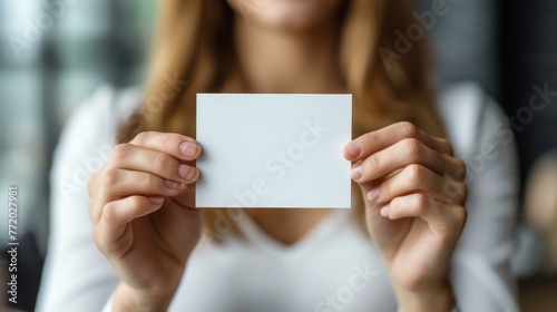 Mockup with beautiful manicured hands holding a 5 inches wide by 7 inches length, blank invitation card vertically, light background. photo