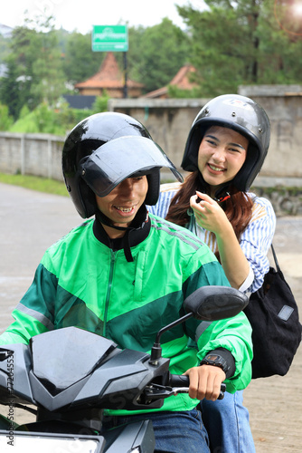 Female Passenger SMiling to the Ojek Driver Online, Showing Direction