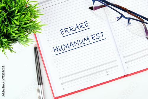 Latin quote Errare humanum est, meaning It is human nature to make mistakes. Mistakes are inherent in human existence. Text written in a notebook on the table