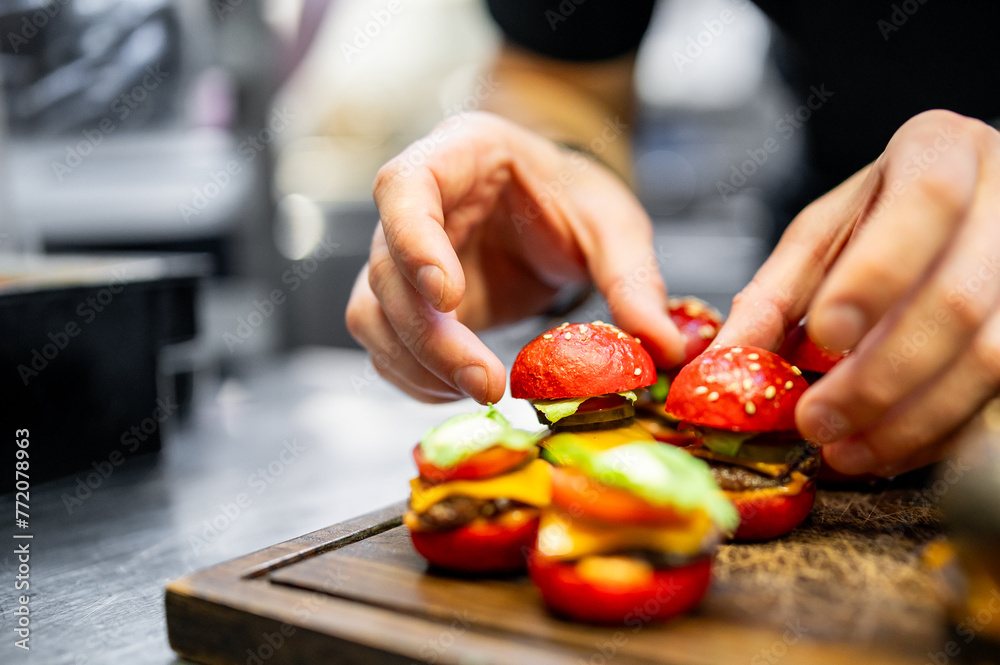  skilled chef meticulously assembles a vibrant mini burgers on a wooden board, showcasing culinary artistry