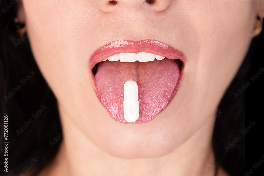 Naklejka premium White oval tablet, capsule on the tongue of a girl, woman, close-up. Placebo concept.