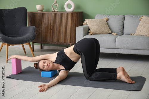 Sporty young woman practicing yoga with blocks at home