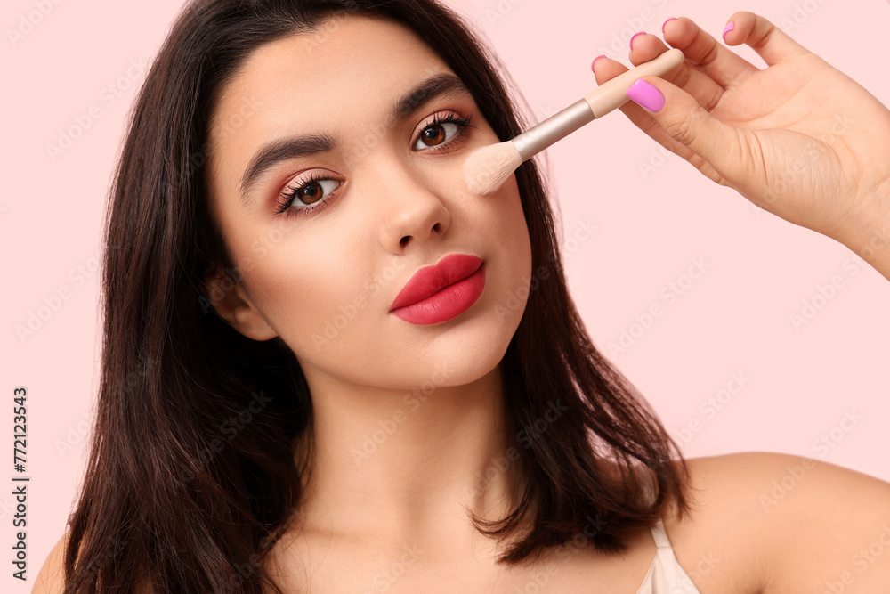 Beautiful young woman with stylish makeup and brush on pink background Beautiful young woman with stylish makeup and brush on pink background