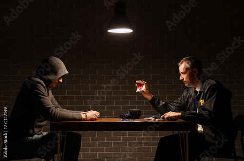 Mature FBI agent questioning suspect in interrogation room