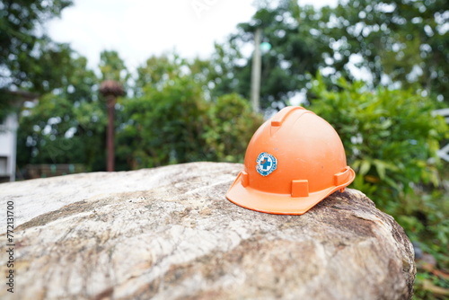 Orange safety helmet on the stone in the construction site power distribution station, stock photo