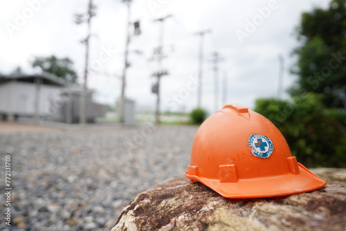 Orange safety helmet on the stone in the construction site power distribution station, stock photo