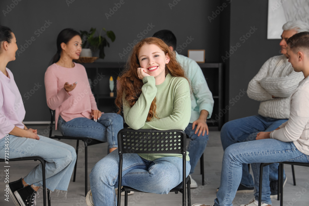 Smiling young woman sitting at group therapy session Smiling young woman sitting at group therapy session