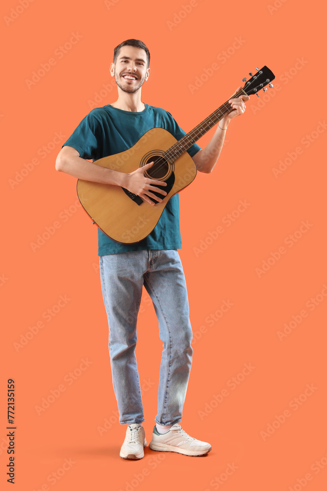 Handsome young man with guitar on orange background Handsome young man with guitar on orange background