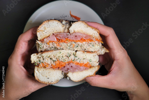 Top view of hands holding a bagel sandwich, ready to eat.