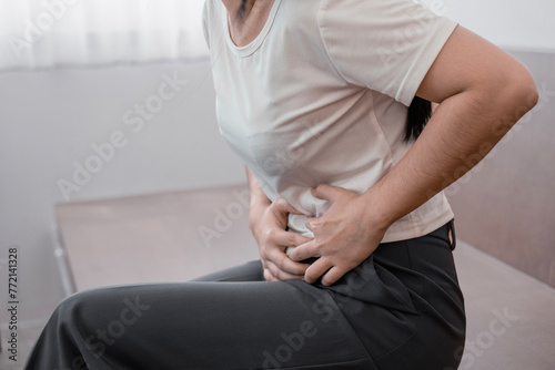 young woman hands in belly, stomach pain from food poisoning, abdominal pain and digestive problem, gastritis or diarrhoea. Abdomen inflammation, menstrual period people. photo